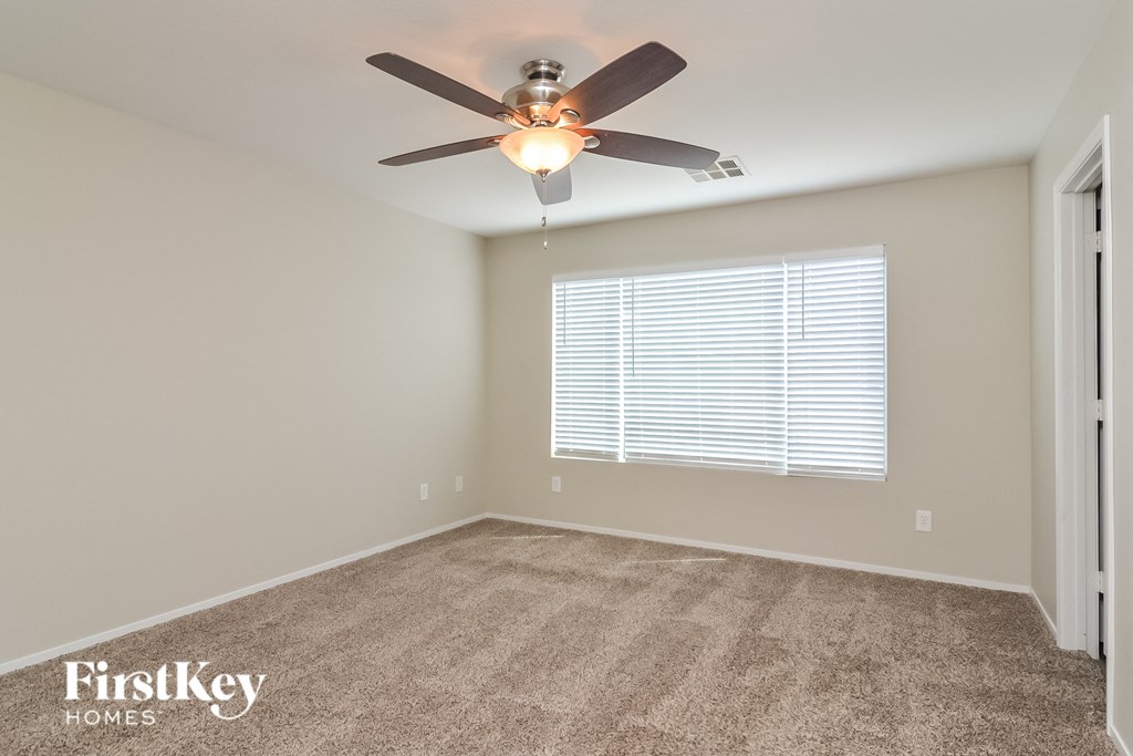 the spacious living room with carpeted flooring and a ceiling fan