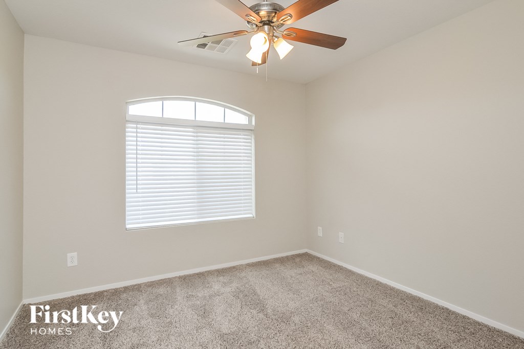the bedroom has a ceiling fan and a carpeted floor