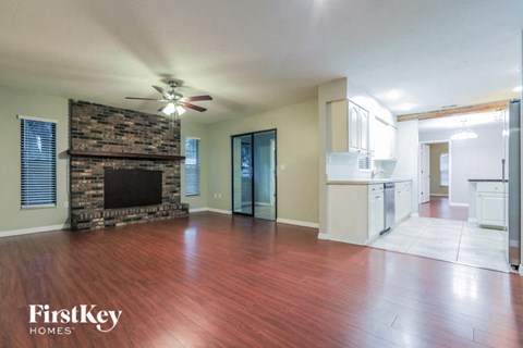 an empty living room with a fireplace and wooden floors