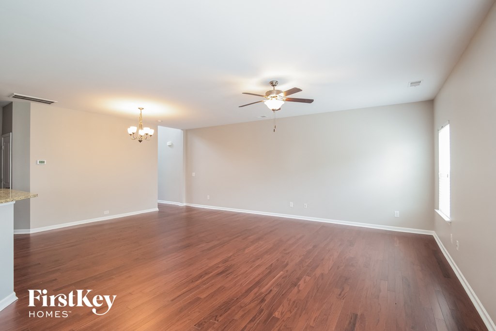an empty living room with wood floors and a ceiling fan