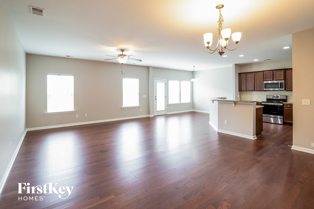 an empty living room and kitchen with wood flooring