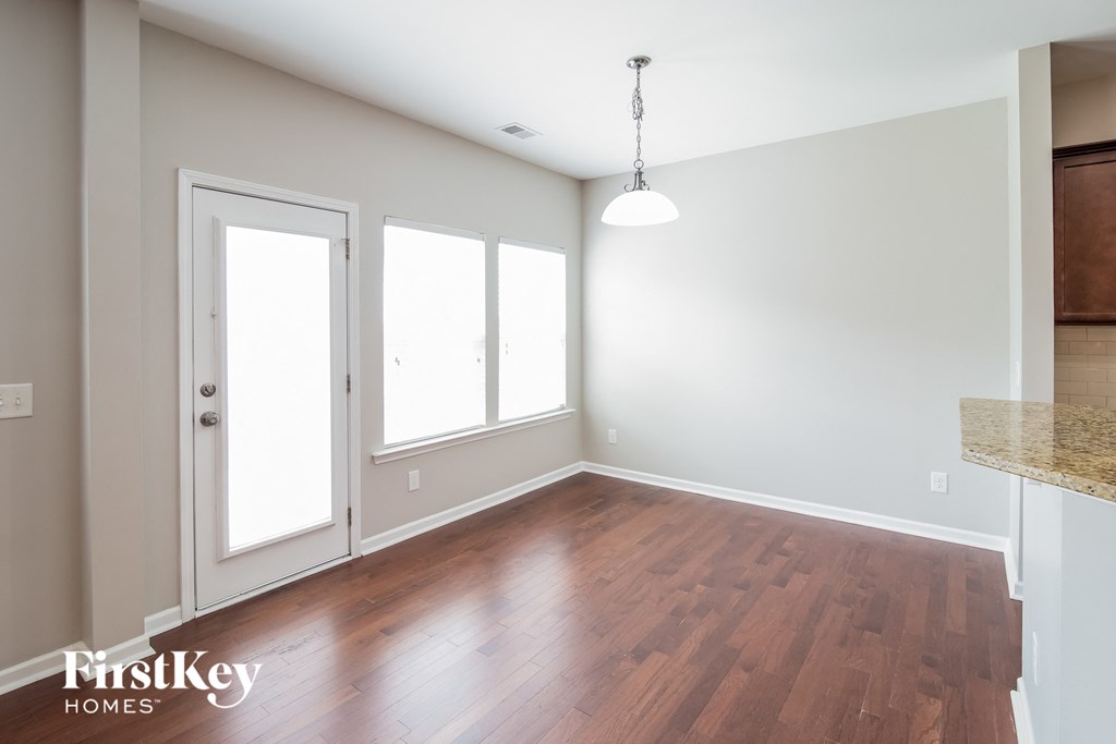 an empty living room with hardwood floors and a kitchen
