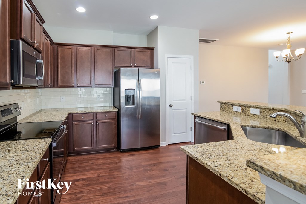 a kitchen with granite counter tops and stainless steel refrigerator