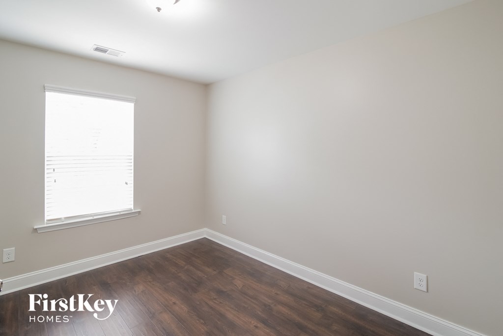 a bedroom with wood floors and white walls and a window