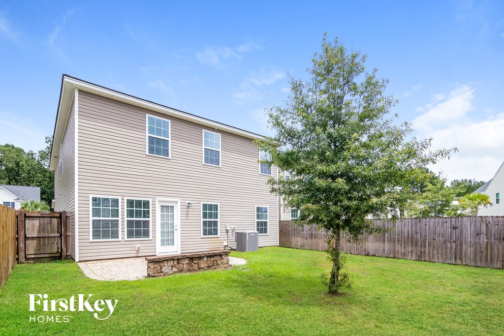 a backyard with a house and a tree in the grass