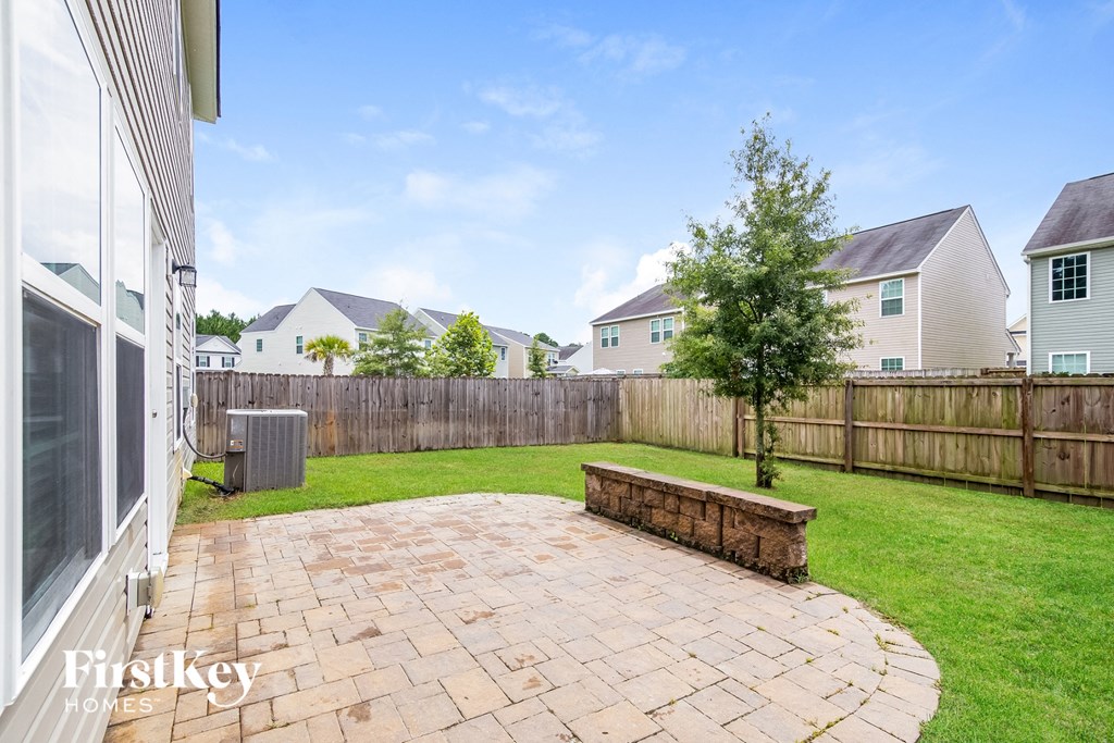 a backyard with a brick patio and a wooden fence