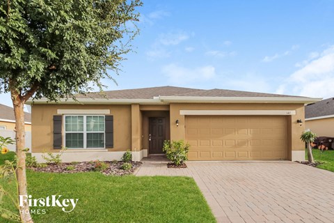 a beige house with a garage door and a lawn