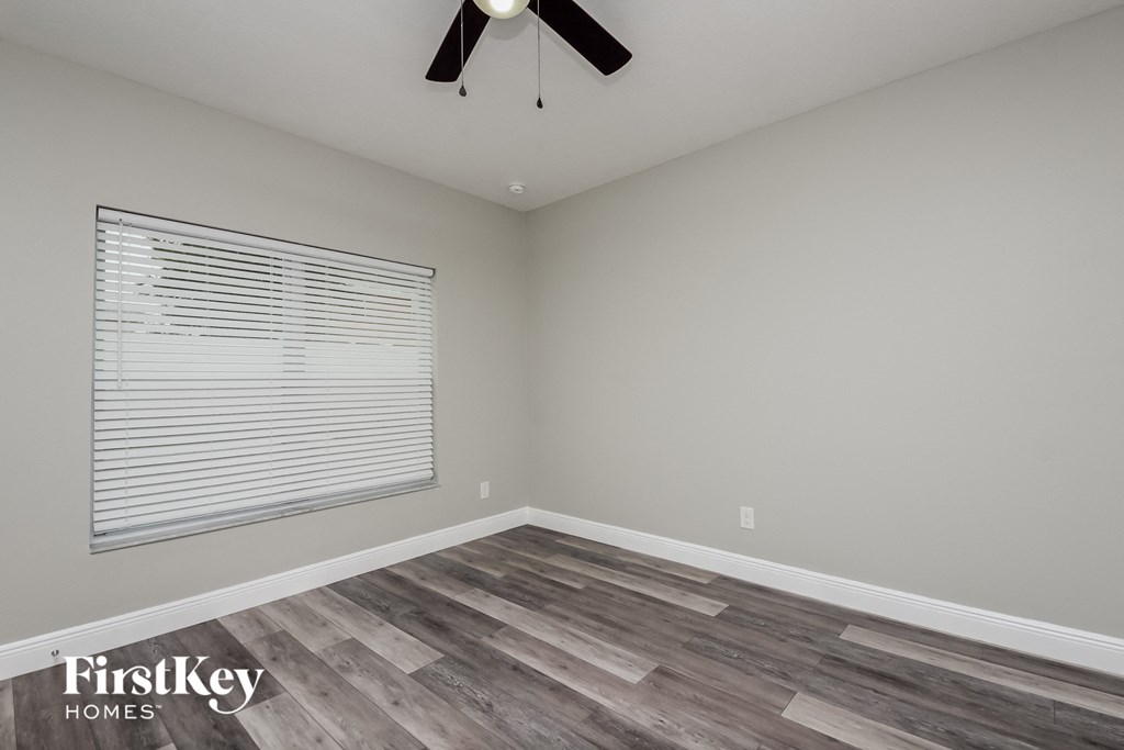 the bedroom has a large window and hardwood flooring