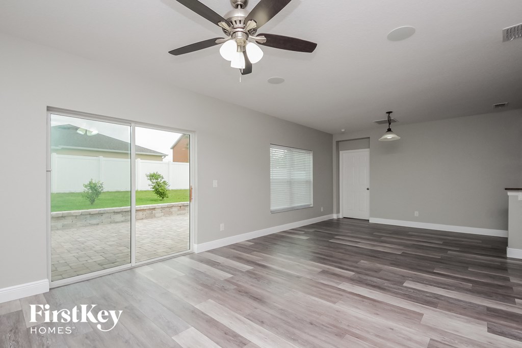 an empty living room with a ceiling fan and sliding glass doors