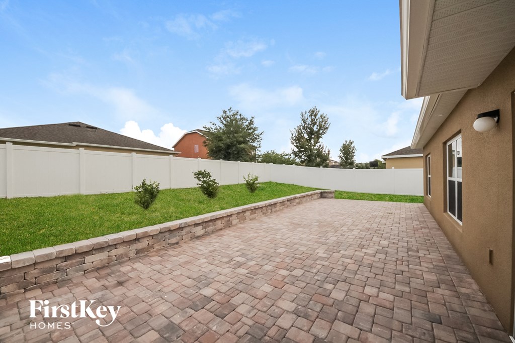 a brick driveway with a white fence in the background