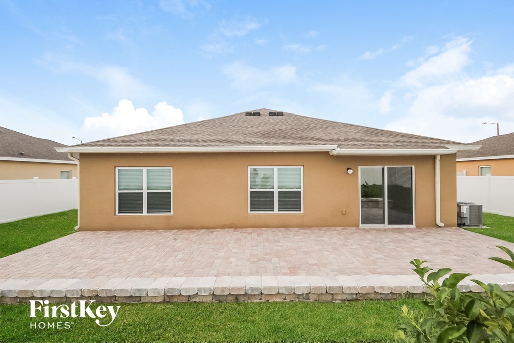 a beige house with a brick driveway and grass