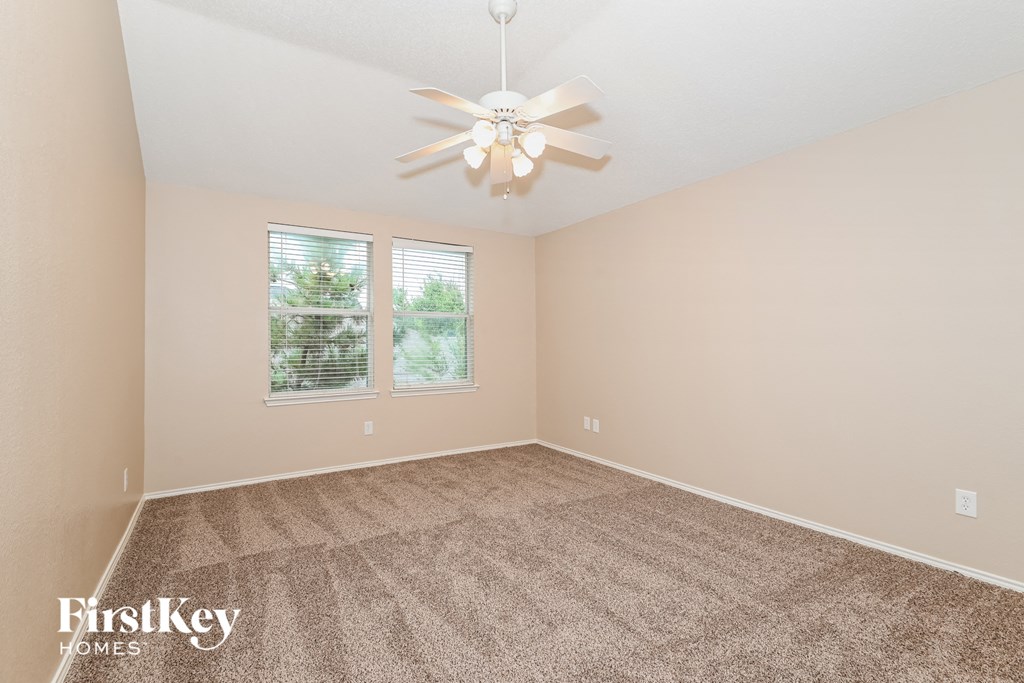 a spacious living room with carpet and a ceiling fan