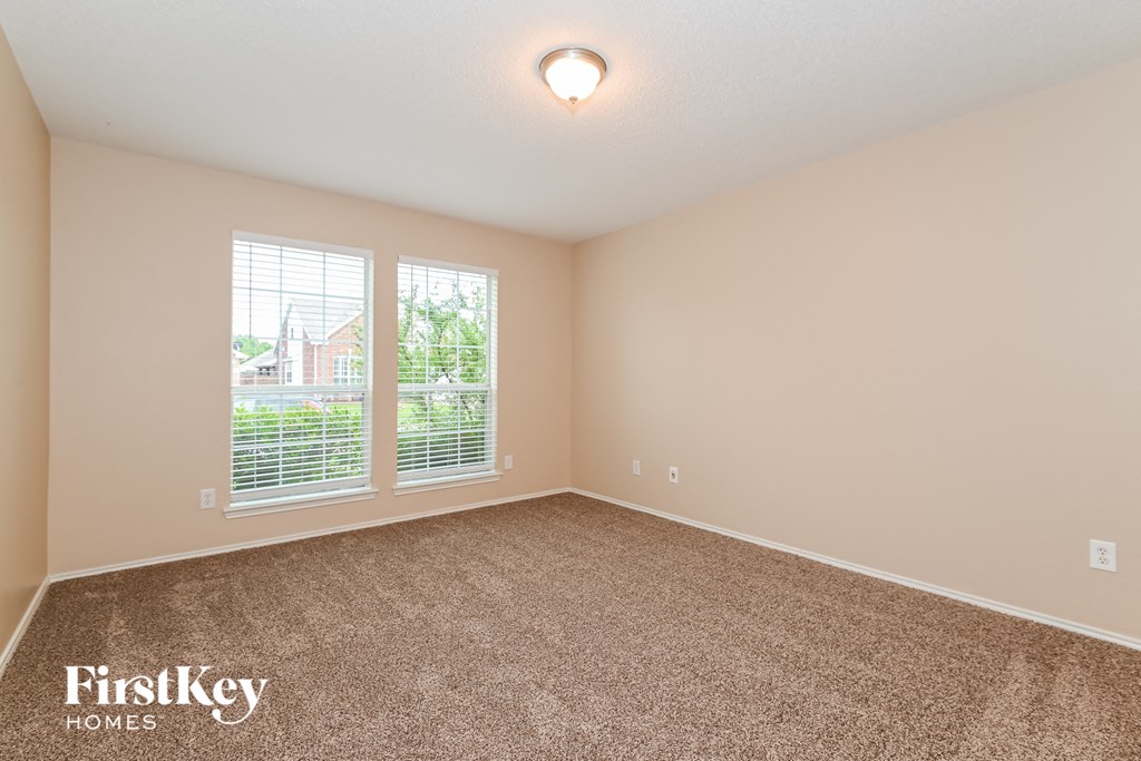 the spacious living room with two windows and carpeting