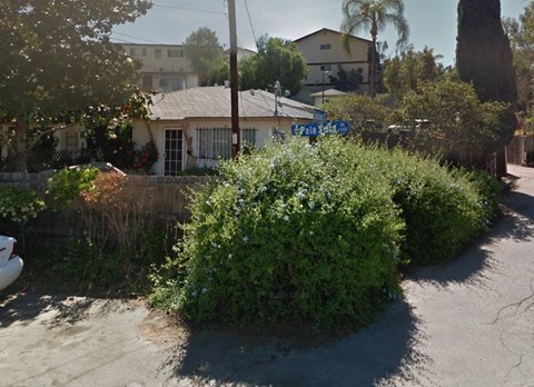 a house with a street sign in front of a bush