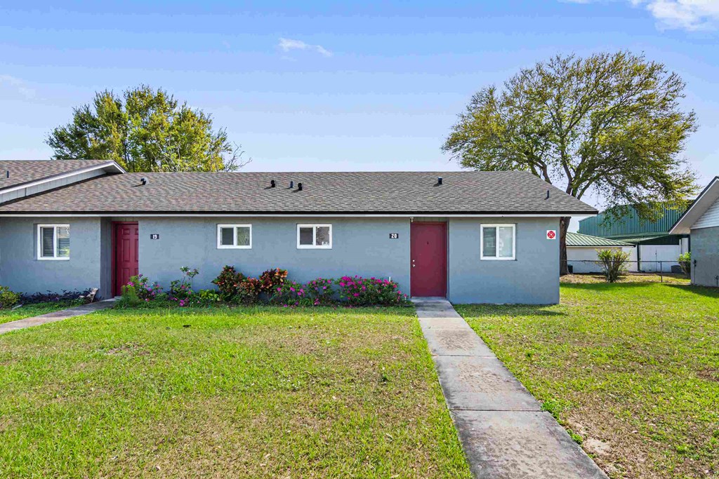 a small blue house with red doors and a lawn