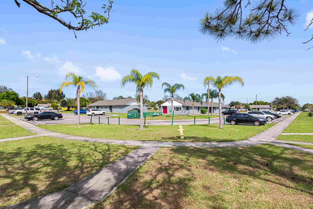 a yellow fire hydrant sitting in the grass near a parking lot