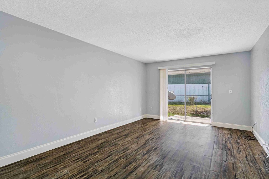 an empty living room with a sliding glass door to a yard
