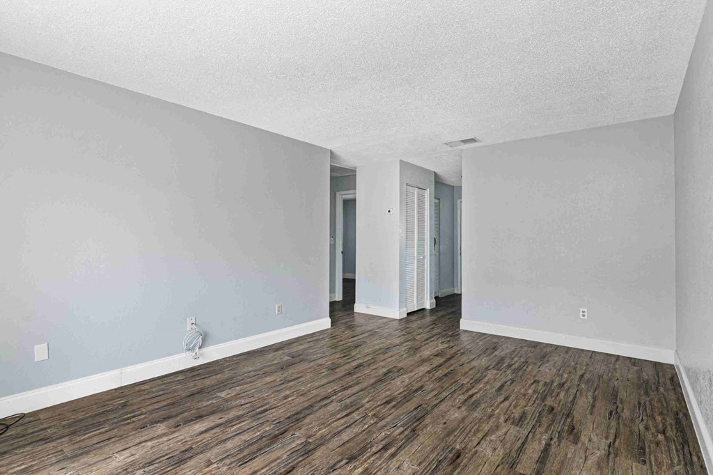 an empty living room with white walls and wood floors