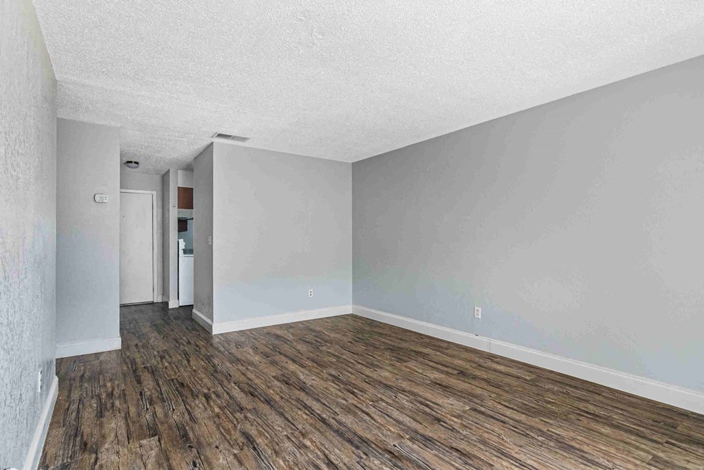 an empty living room with a wood floor and white walls