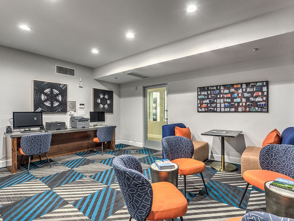 a lounge area with chairs and a desk with a computer