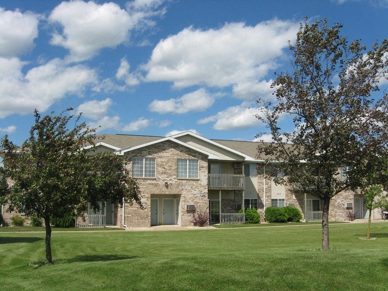 an apartment building with a lawn and trees