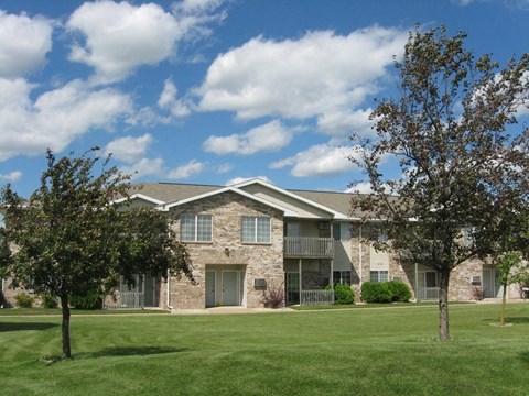 an apartment building with a lawn and trees