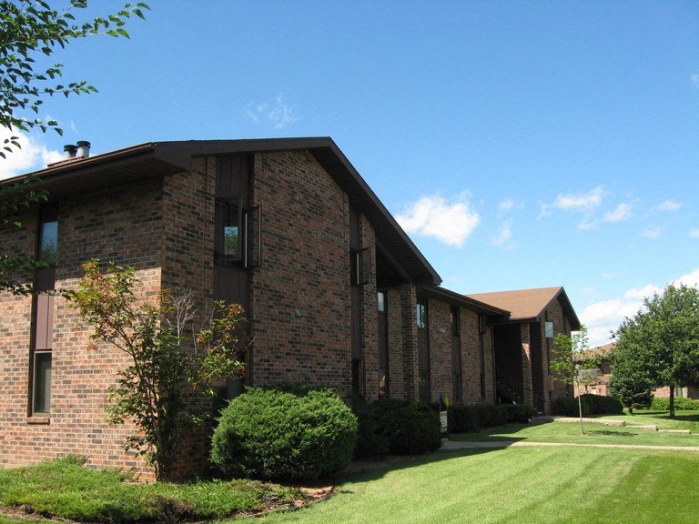 a brick building with a green lawn and a blue sky