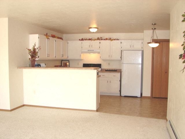 an empty kitchen with white cabinets and a white refrigerator