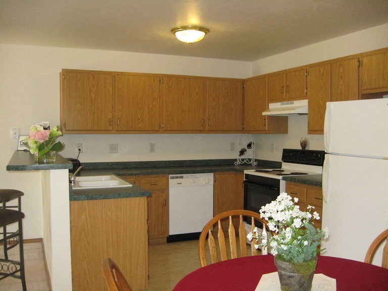 a kitchen with wooden cabinets and a red table and chairs