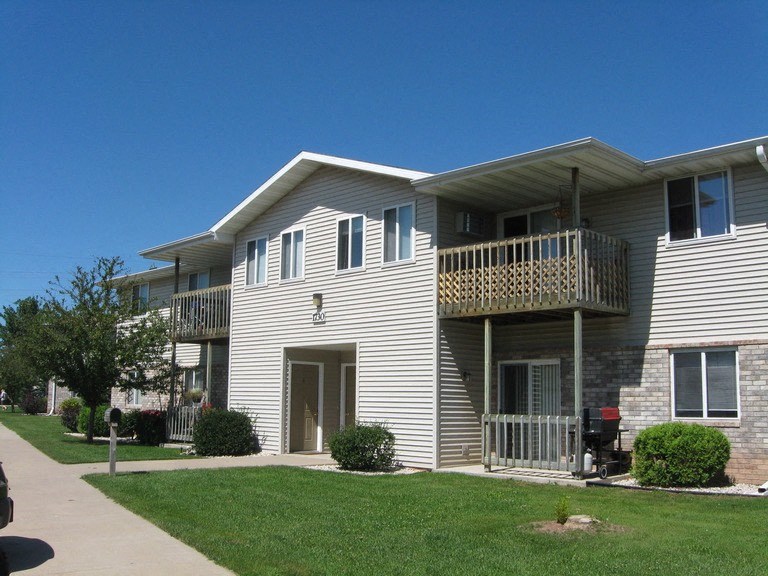 an apartment building with a porch and a lawn