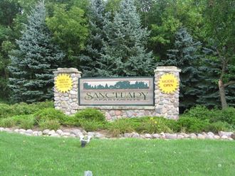a sign for sansonary park in front of trees
