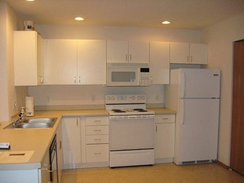 a white kitchen with white appliances and white cabinets