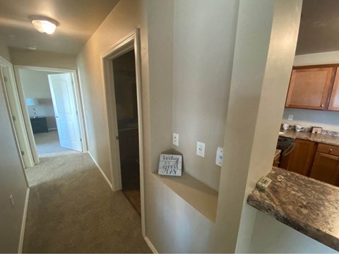a view of a hallway with a kitchen and a hallway mirror