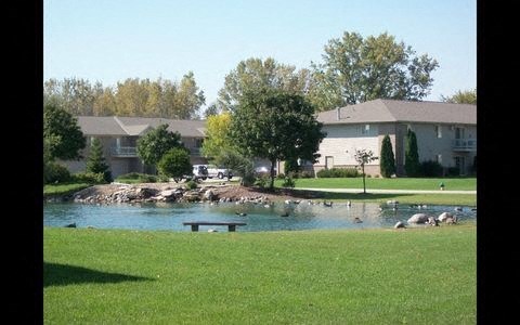 a park with a pond and a house