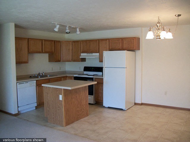 an empty kitchen with white appliances and wooden cabinets
