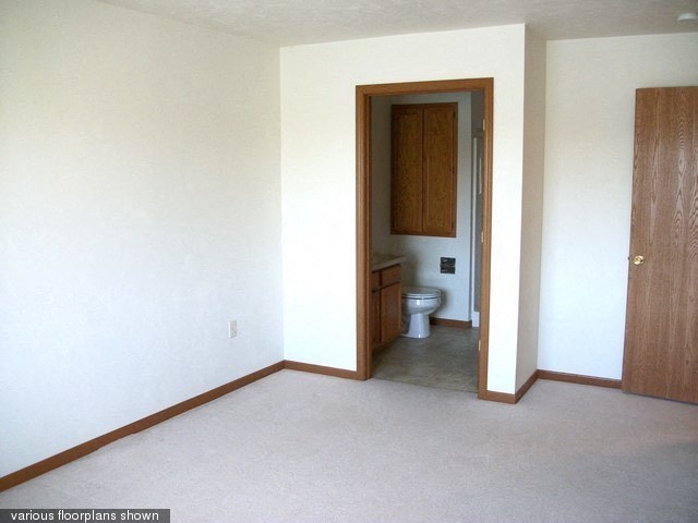 an empty room with a toilet and a door to a bathroom