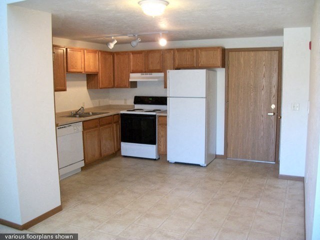 an empty kitchen with a refrigerator and a sink