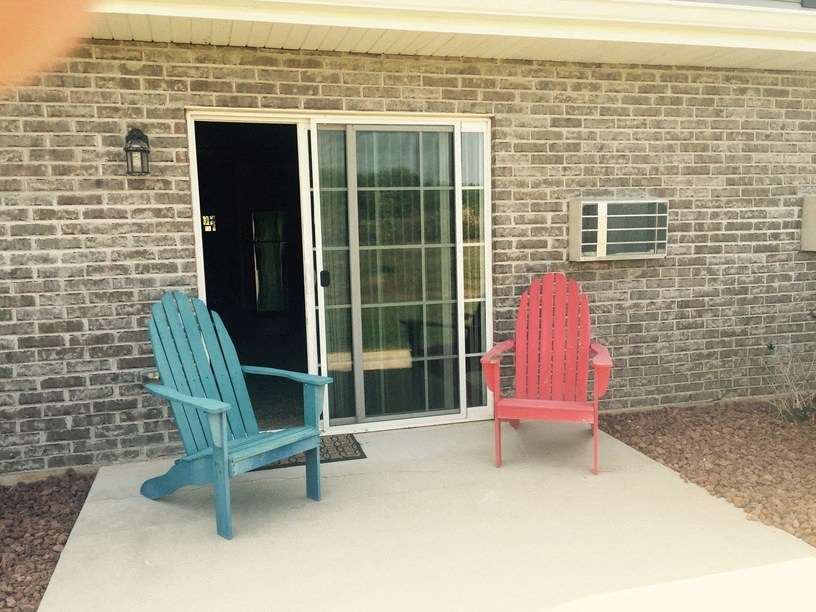 two blue and red chairs on a porch in front of a brick wall