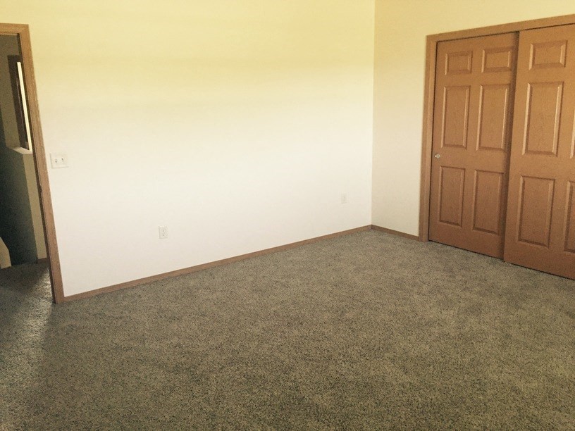an empty room with a door and a carpeted floor