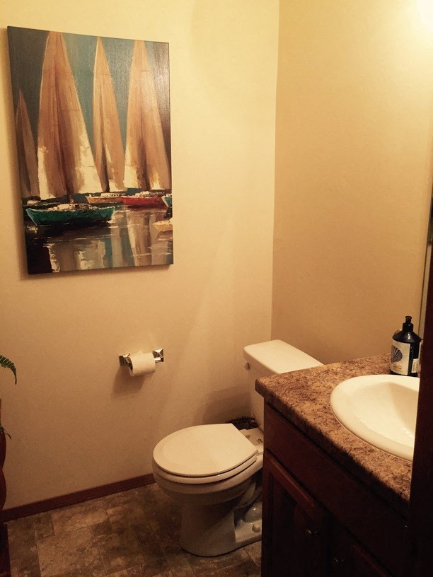 a bathroom with a toilet and a painting of sail boats
