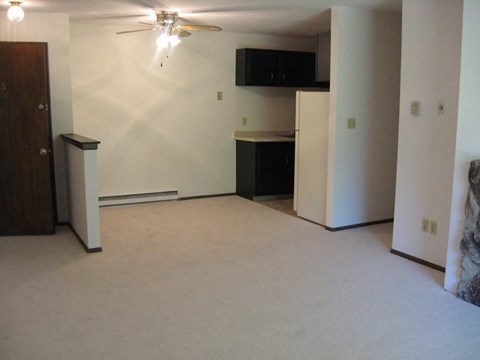 an empty living room and kitchen with a ceiling fan