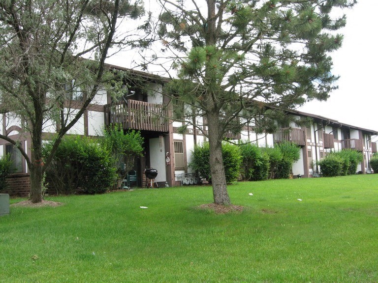 a view of the exterior of an apartment building with grass and trees