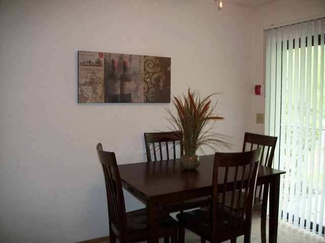 a dining room table with chairs and a painting on the wall
