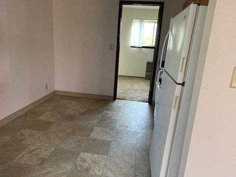 an empty room with a white refrigerator in it