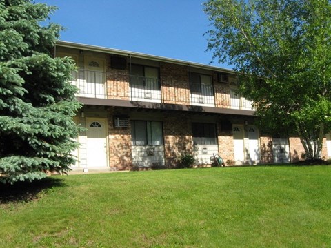 an apartment building with a green lawn and trees