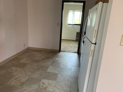 an empty room with a white refrigerator in it