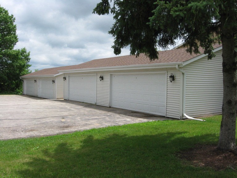 a white garage with a driveway next to a tree
