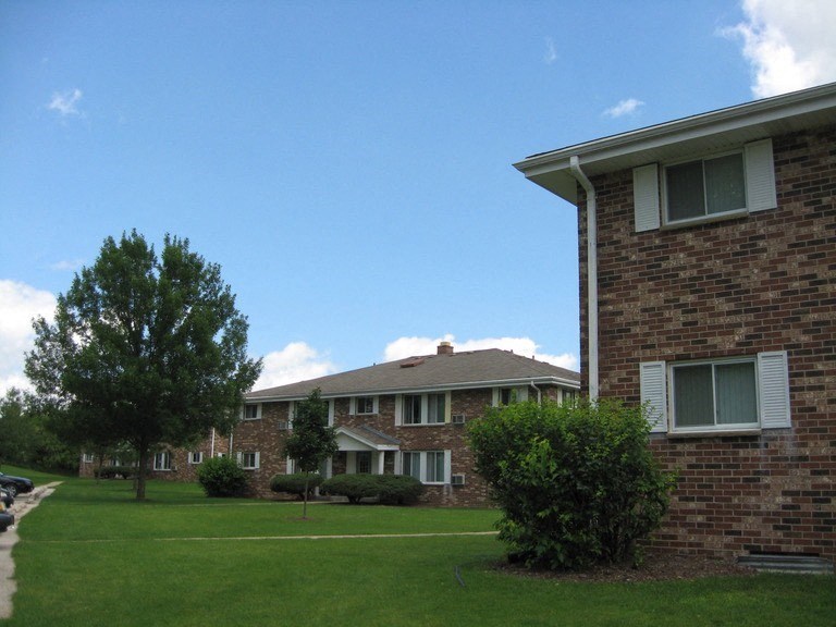 an apartment building with a green lawn and trees