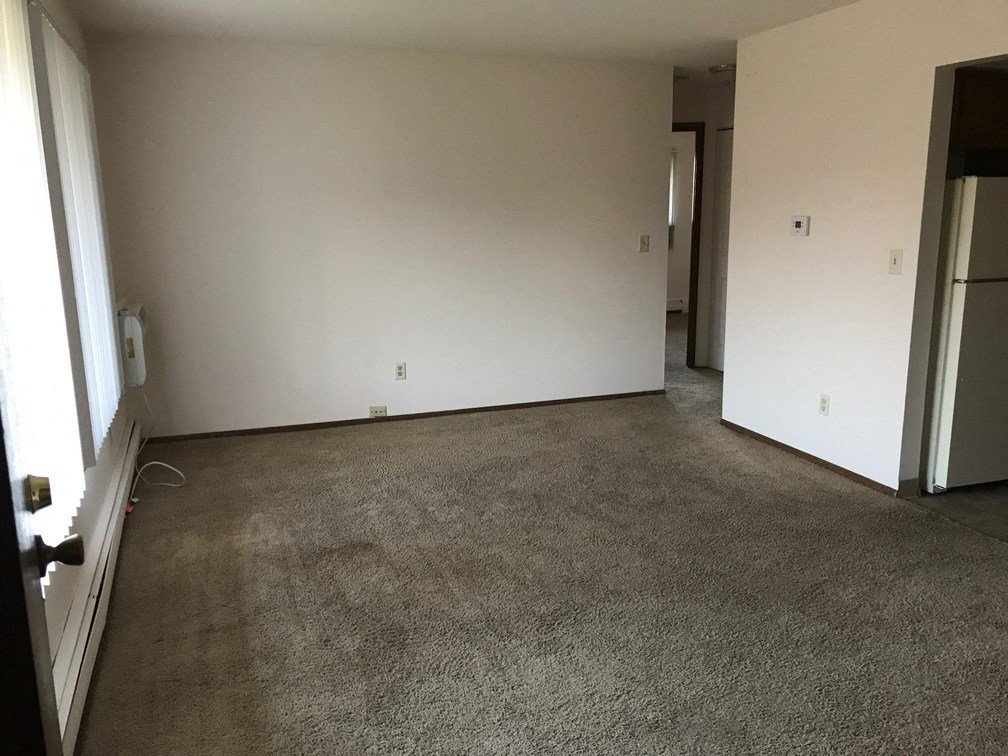 an empty room with a carpeted floor and a refrigerator