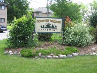 a sign for county square apartments in a garden